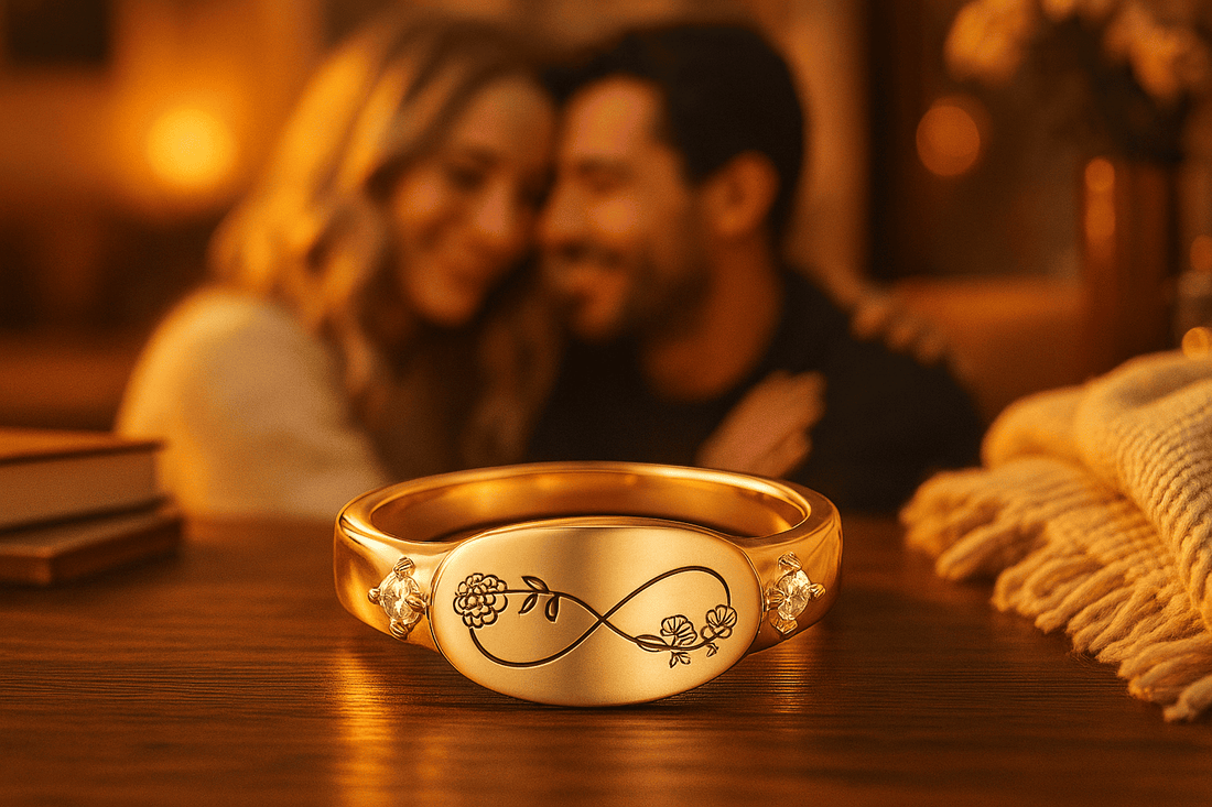 Gold personalized jewelry ring with infinity symbol and floral engravings on wooden table with couple in background - romantic personalized jewelry gifts