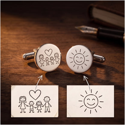 Children's drawings on paper next to the cufflinks engraved with the same drawings