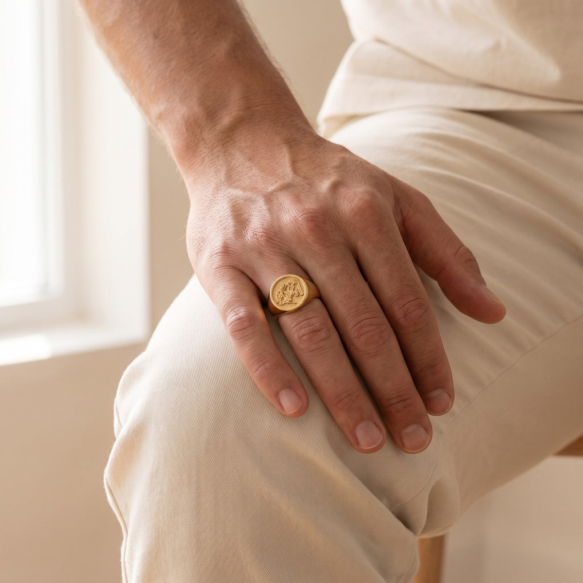 Family signet ring on a man's hand resting on his knee